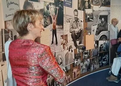 Photo de Jeanne Corporon devant le mur de photographies de Georges Brassens