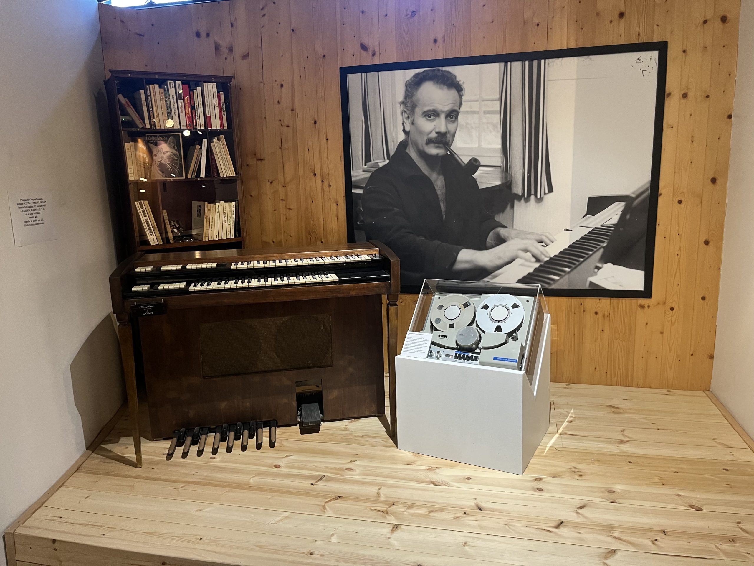 Vue de la scénographie avec l'orgue de Georges Brassens et une photographie en noir et blanc de Brassens jouant de l'orgue