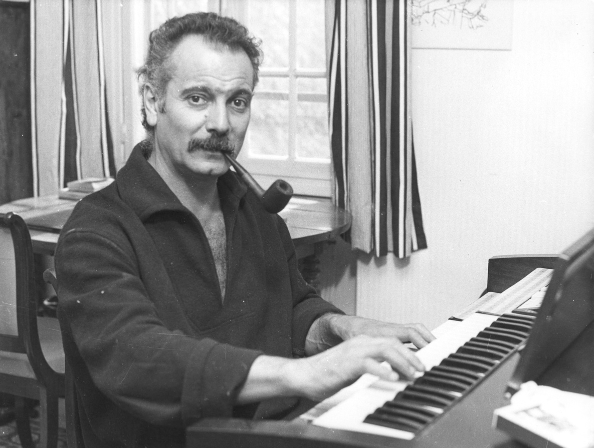 Georges Brassens avec sa pipe en train de jouer devant son orgue.